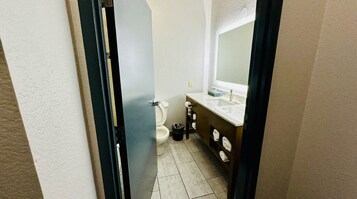 A bathroom with a toilet, sink, and mirror.