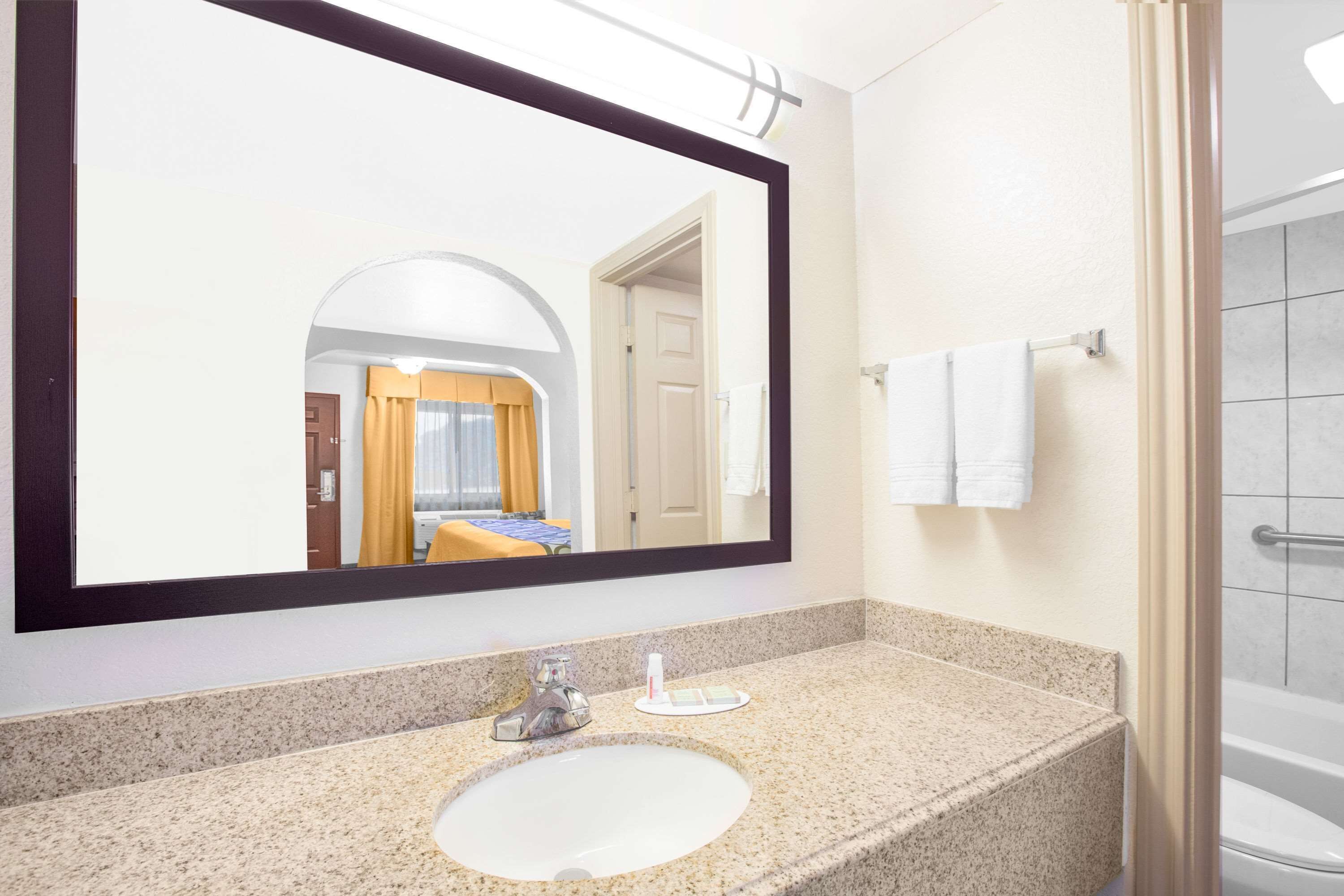Une salle de bain avec un grand miroir, un lavabo et une douche.