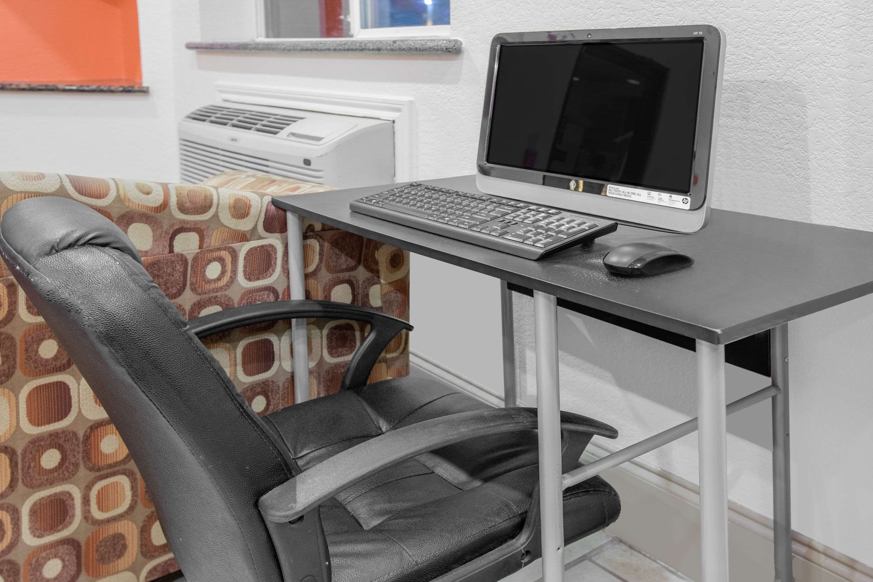 Un espace de travail comprenant un bureau, une chaise, un ordinateur et un clavier.