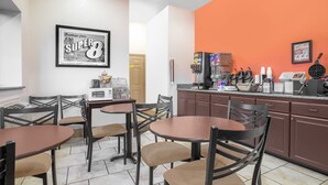 A restaurant interior with tables and chairs, a coffee machine, and a counter with various items. - Super 8 by Wyndham Idabel (Idabel)