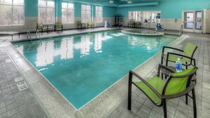 An indoor swimming pool with clear water, surrounded by chairs and tables. - SpringHill Suites Anchorage University Lake (Anchorage)