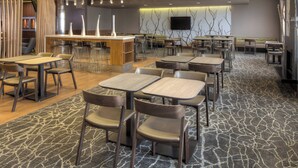 A modern hotel lobby with multiple seating areas, a bar, and a flat-screen TV on the wall. - SpringHill Suites Anchorage University Lake (Anchorage)