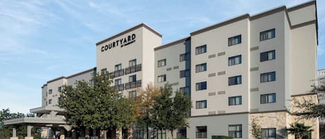 Een Courtyard by Marriott hotel met een modern design, meerdere verdiepingen en een parkeerplaats ervoor.