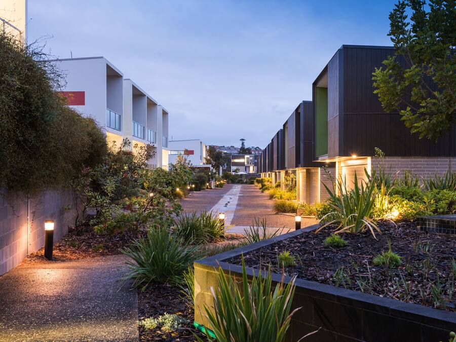 A pathway flanked by modern buildings with a well-maintained garden area.