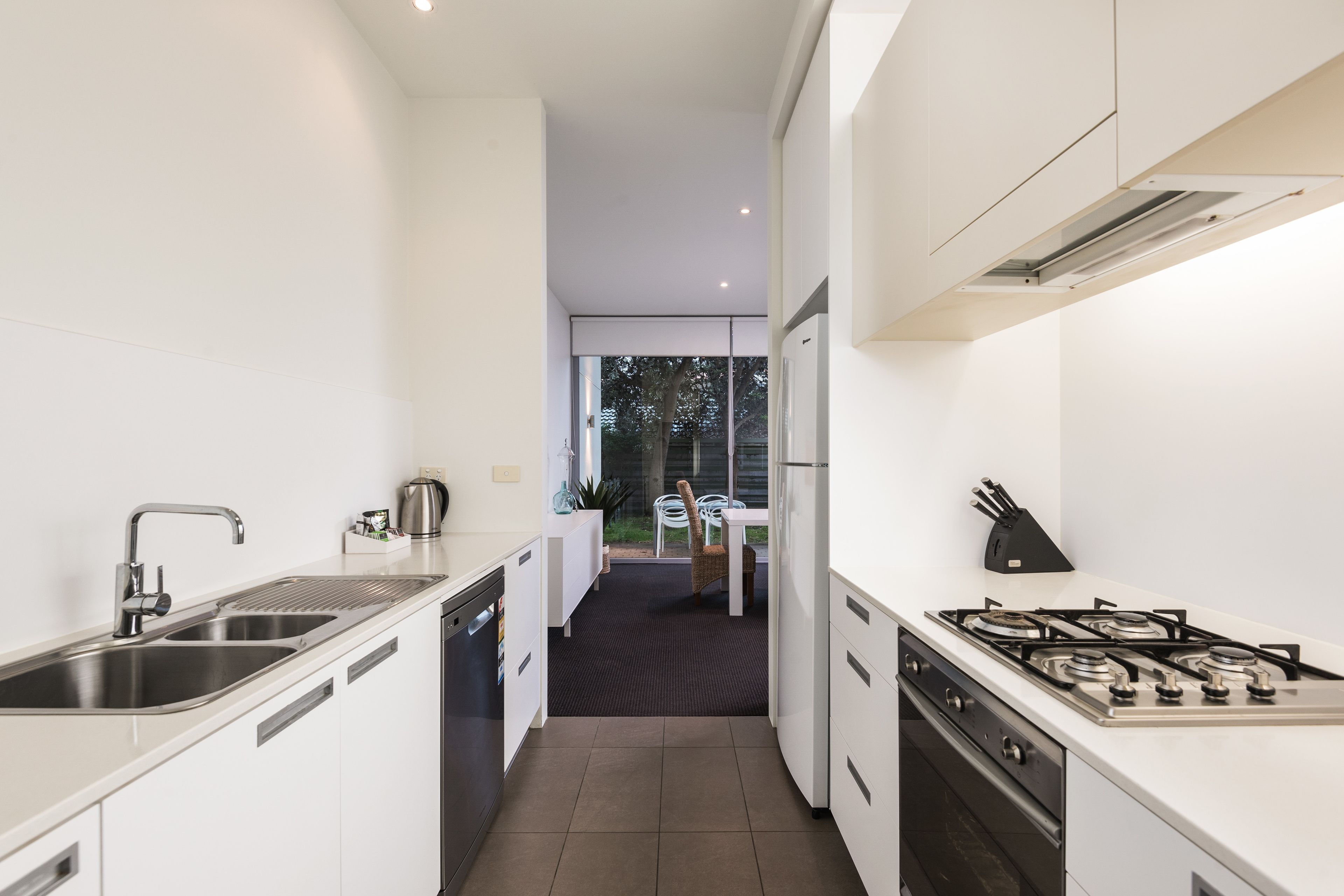 Una cocina moderna con armarios blancos, electrodomésticos de acero inoxidable y una isla central.