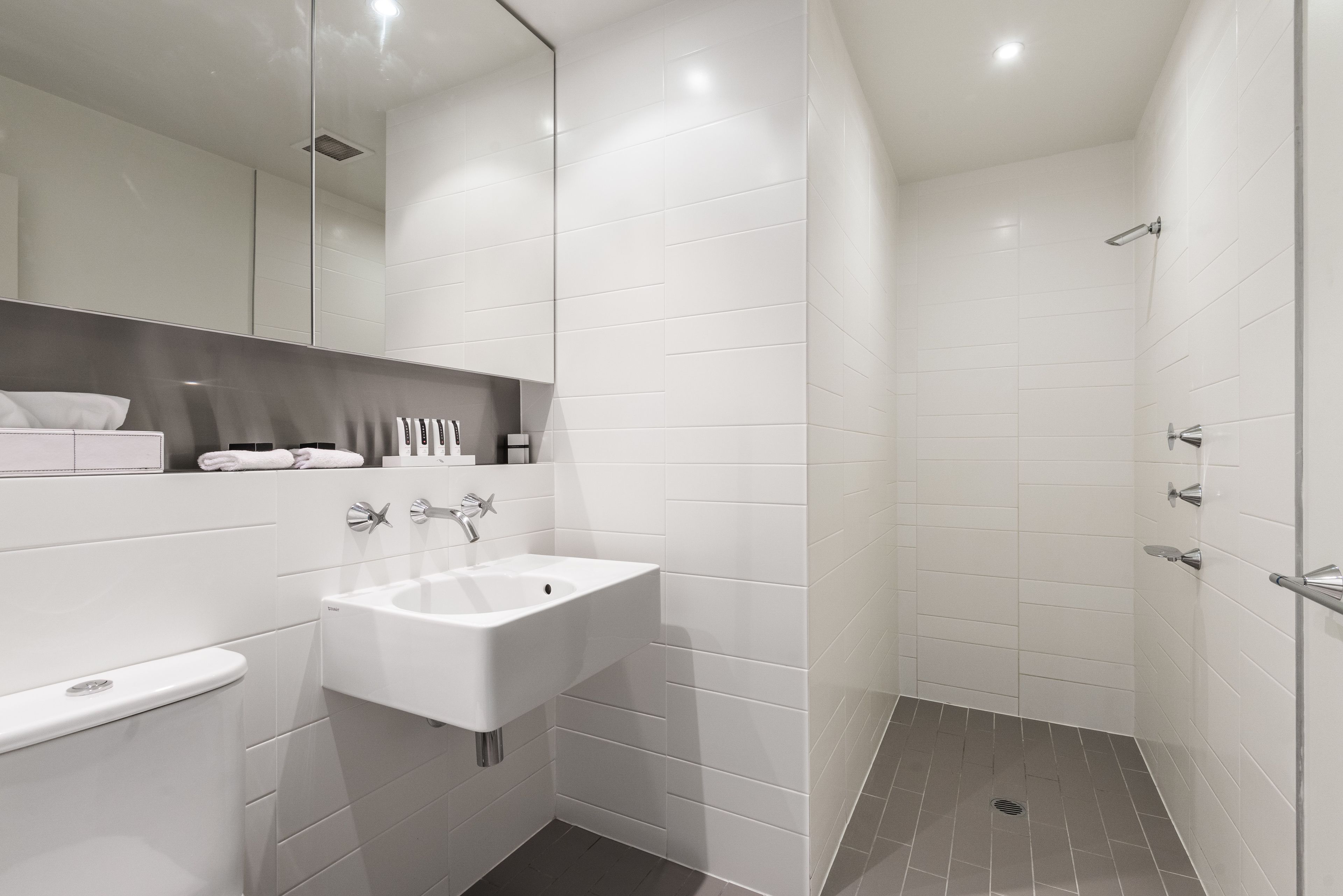 A modern bathroom with a white sink, mirror, and shower.