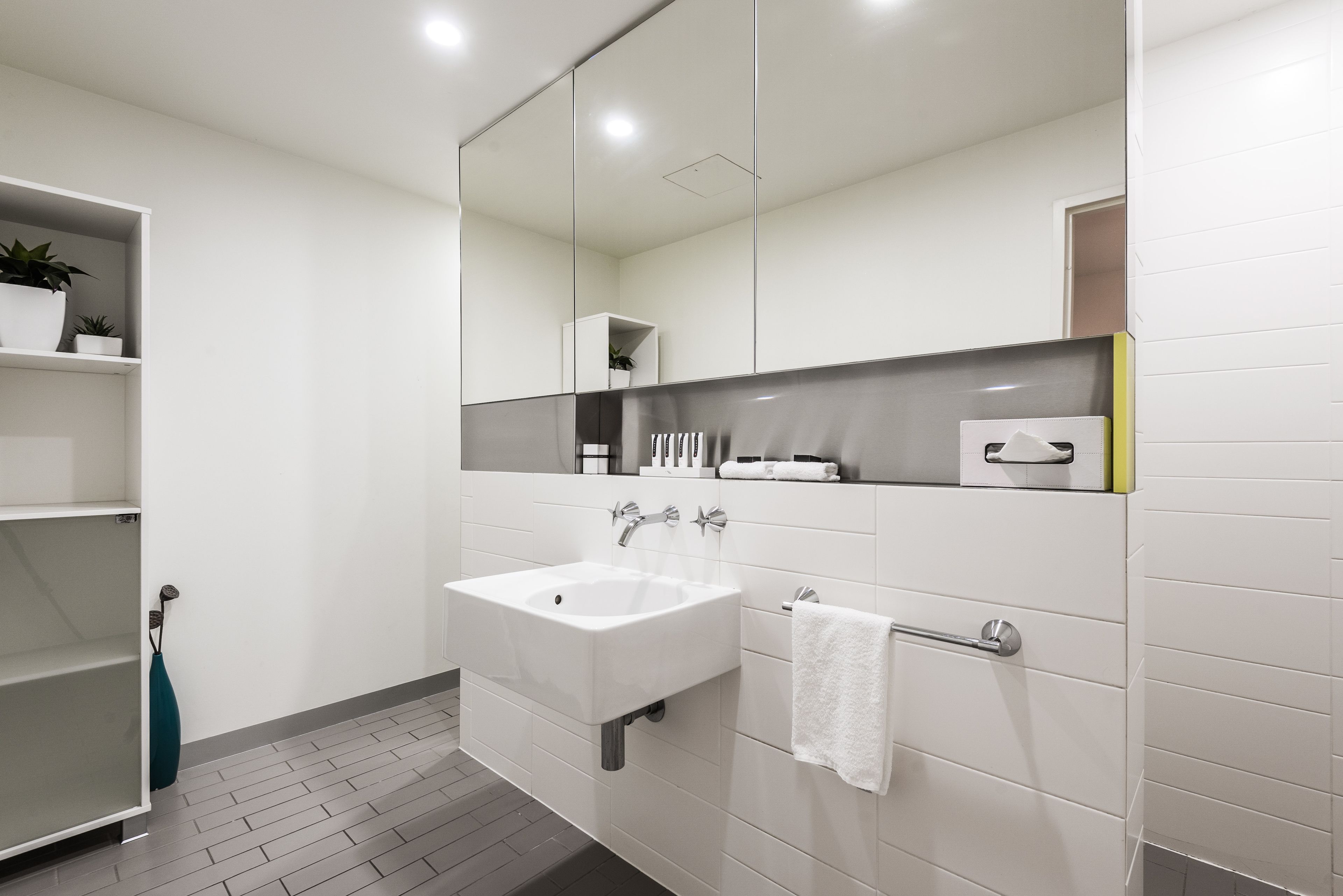 A modern bathroom with a white sink, a towel rack, and a mirror above the sink.