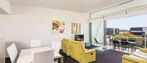 A modern living room with a glass partition, a dining area, and a sofa.