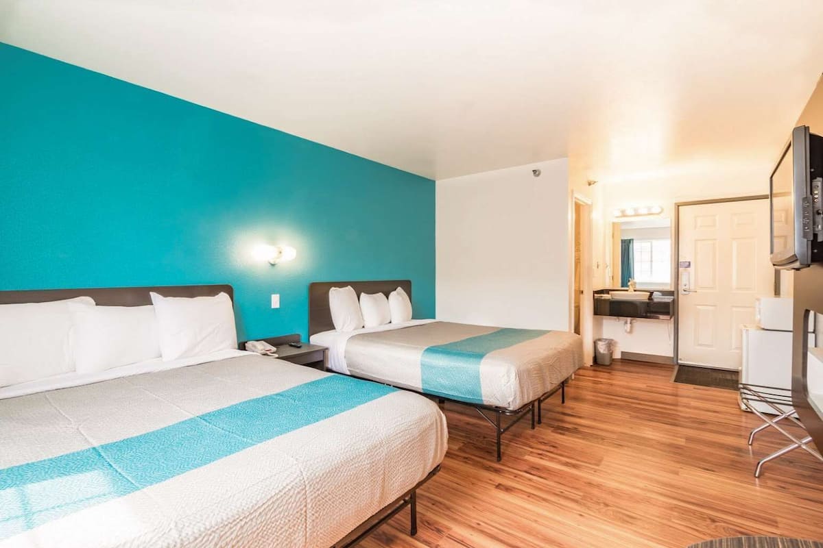 A hotel room with two beds, a bathroom, and a TV.