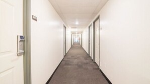En lang, smal hotelgang med døre på begge sider, et tæppe på gulvet og et loft med indbyggede spots.