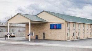 Et motel med en etagers bygning, et overdækket parkeringsområde og et skilt med nummer '6'.