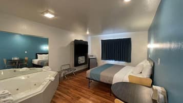 A compact hotel room with a bed, a small table, a chair, a sofa, a bathtub, and a microwave.