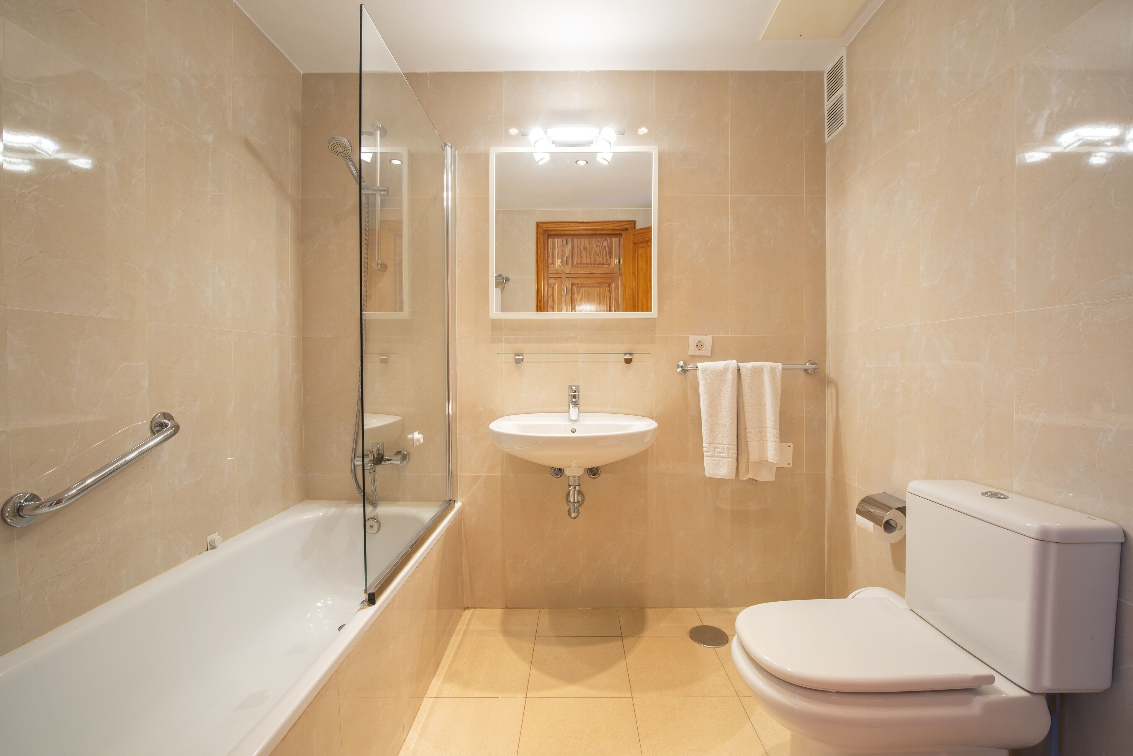 Un baño moderno con ducha envuelta en vidrio, lavamanos e inodoro.