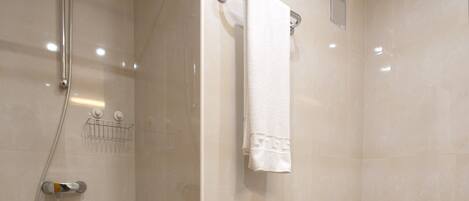 A bathroom with a shower, toilet, and a towel rack.