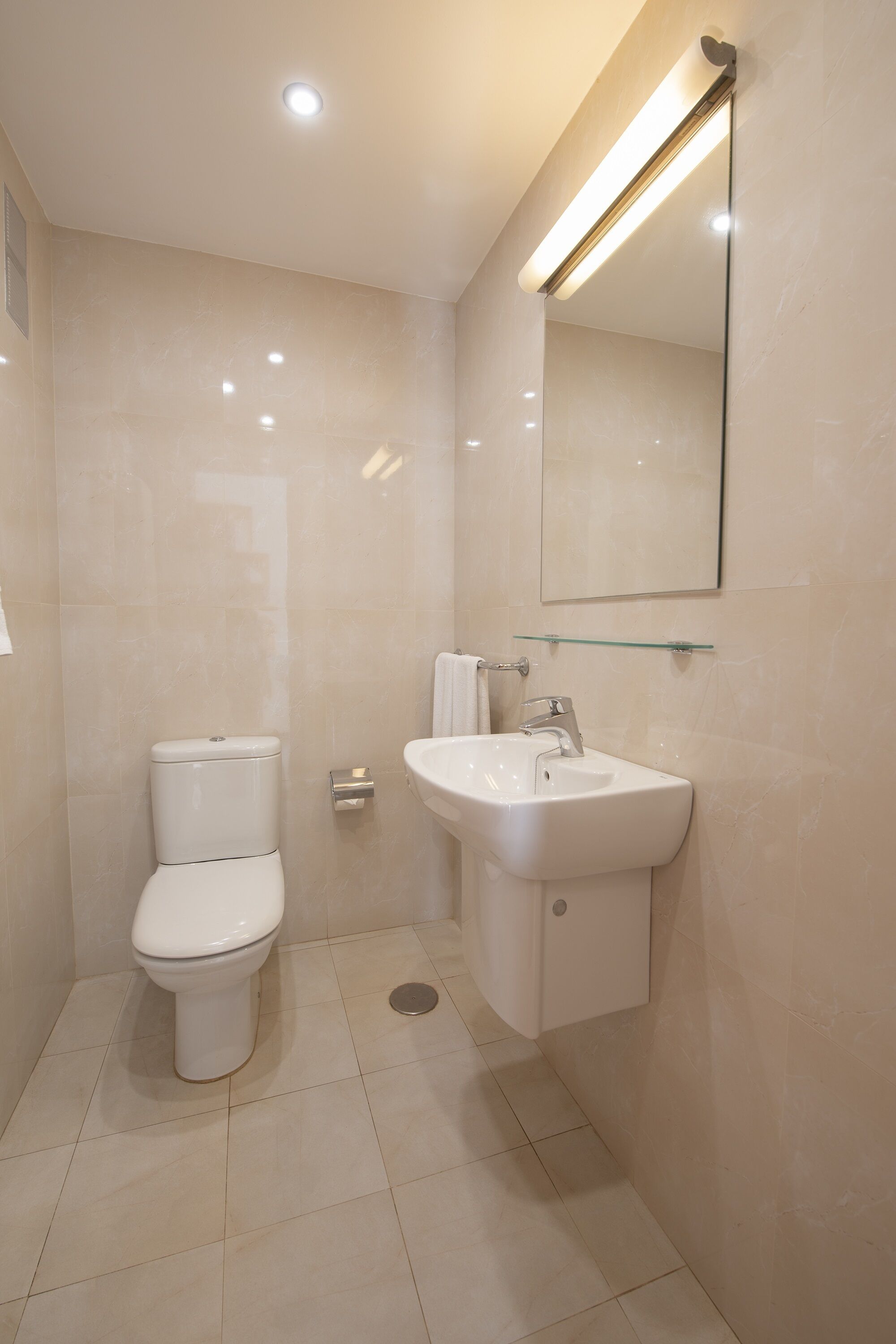 A modern bathroom with a toilet, sink, and mirror.