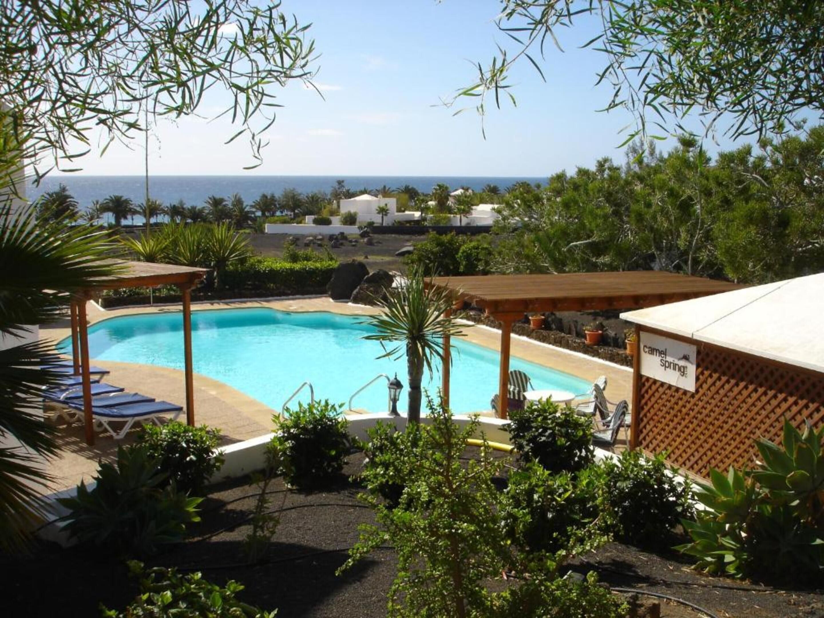 A pool area with lounge chairs and a view of the ocean.
