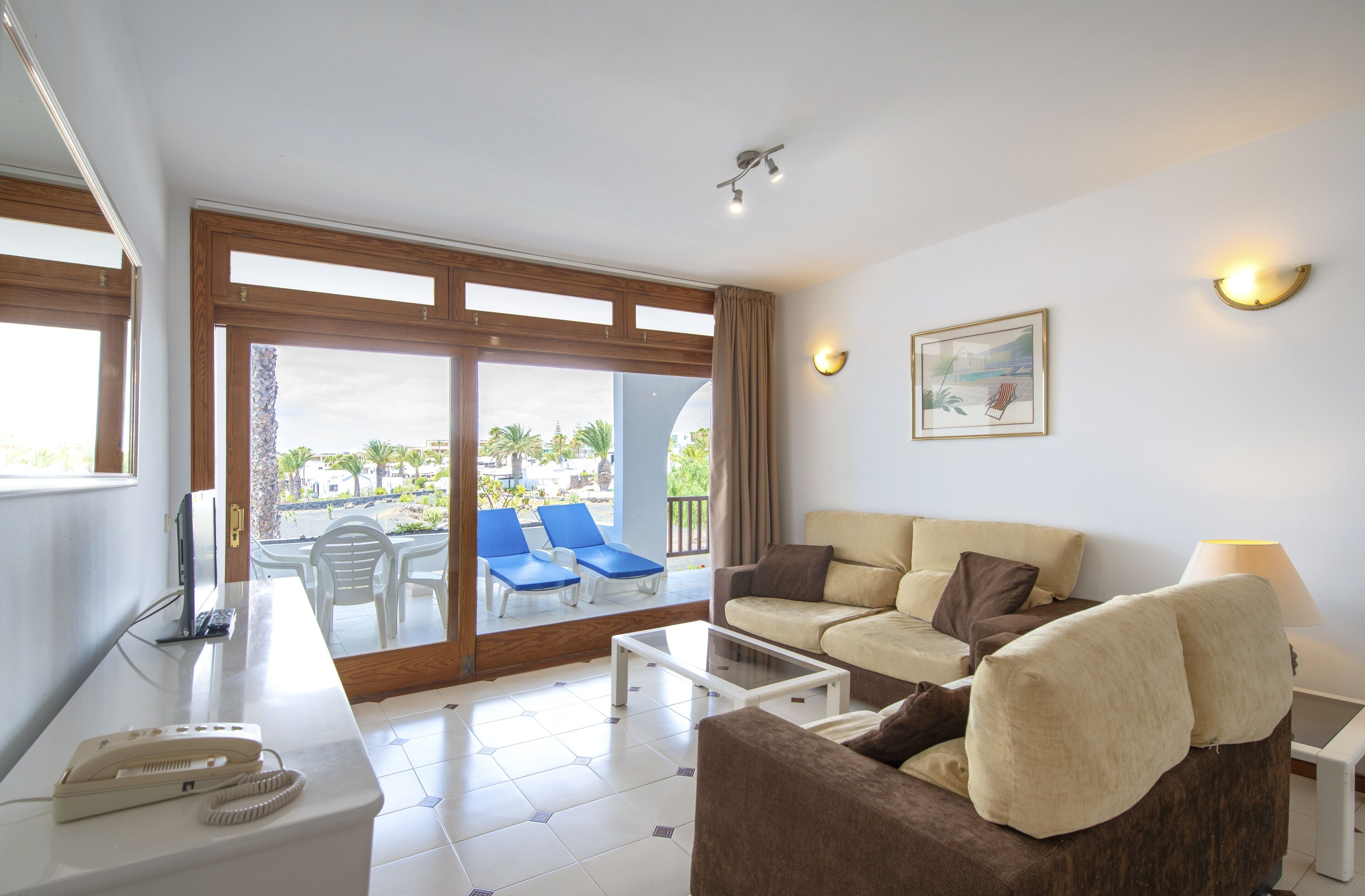 Un salon moderne avec un canapé, une table basse et une vue sur un balcon équipé de chaises.
