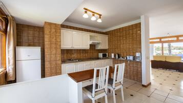 Una cocina con armarios blancos, una mesa de madera y un microondas.