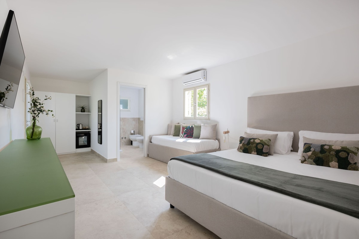 Une chambre moderne avec un grand lit, une télévision et une petite kitchenette.