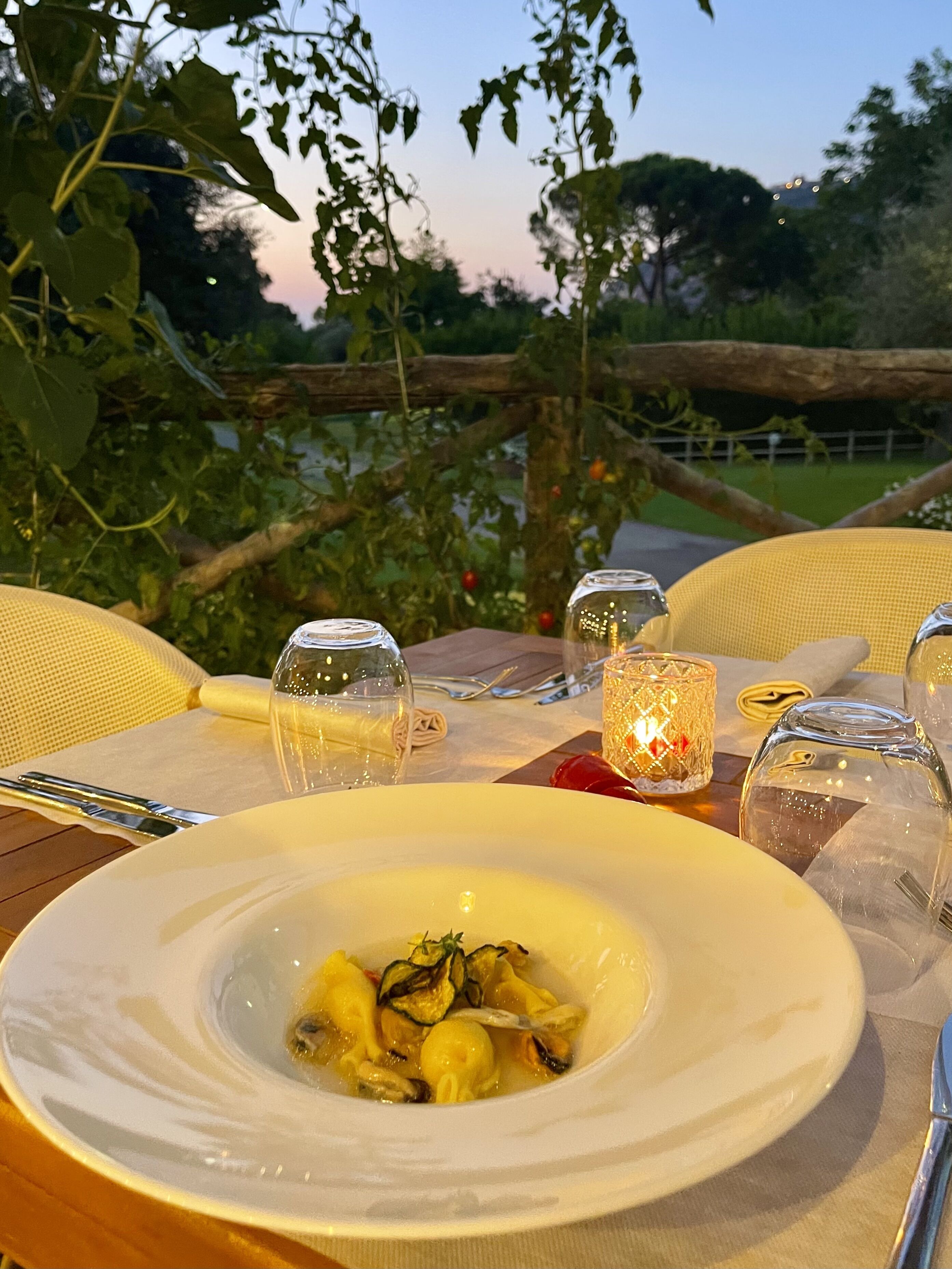 A table set for a meal with a bowl of food, glasses, and a candle.