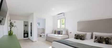 Una habitación de hotel moderna con una cama grande, una encimera verde, un televisor, un baño y una pequeña zona de cocina.