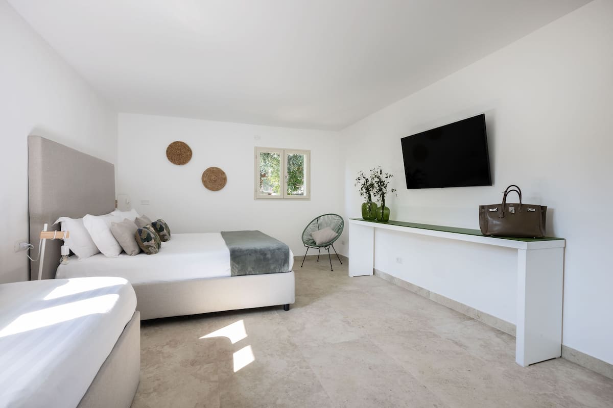 A modern bedroom with a bed, bedside table, and a TV mounted on the wall.