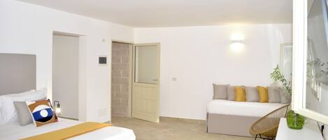 Una habitación de hotel moderna con una cama, un sofá, una silla y un escritorio.