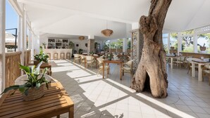 A spacious indoor area with wooden furniture, a large tree trunk centerpiece, and a variety of plants. - Sopramare Resort (Piano di Sorrento)