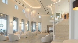 Un interior espacioso y moderno, con techos altos, ventanas amplias y una escalera que sube a un nivel superior.