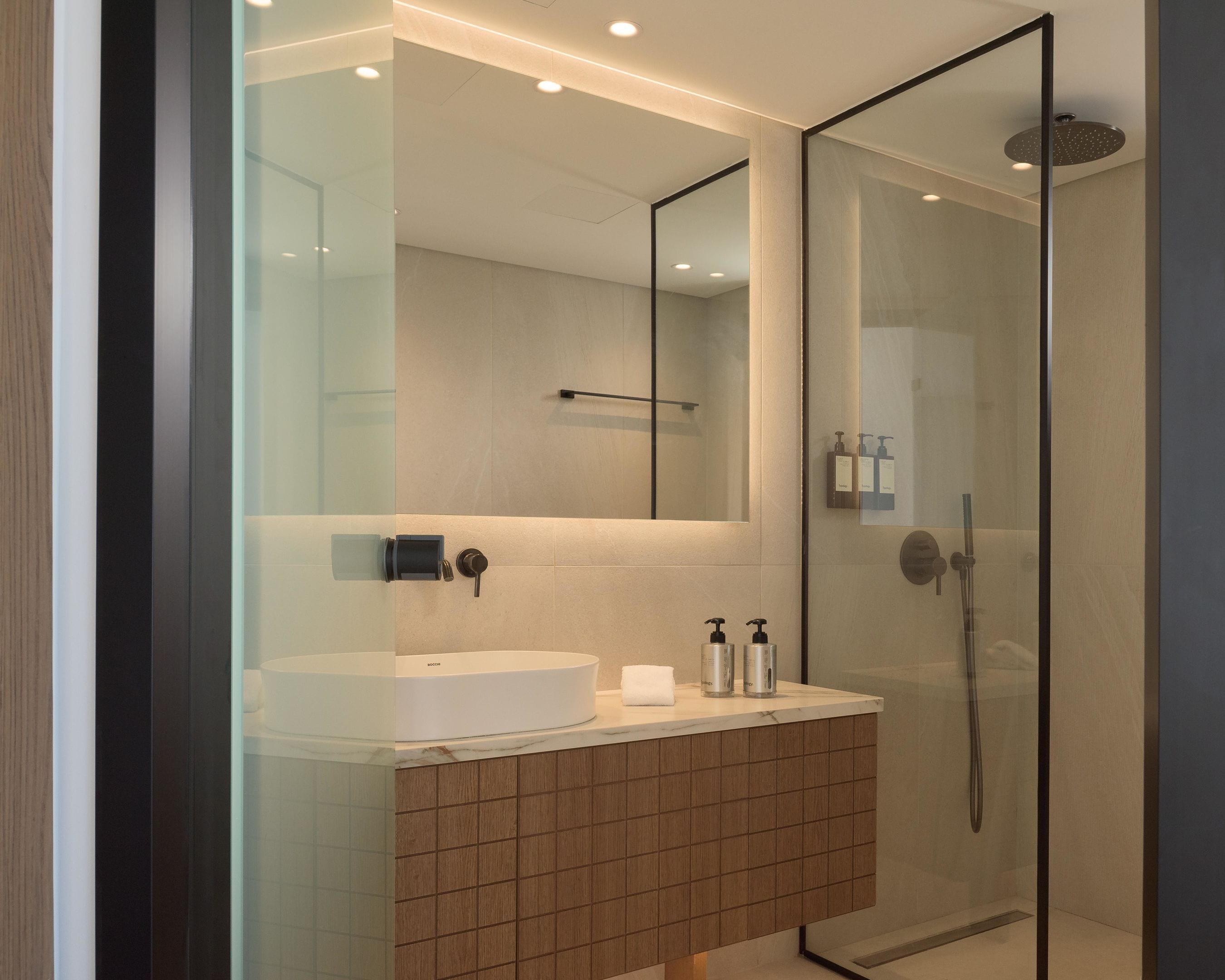 Un bany modern amb dutxa amb envàs de vidre, un lavabo blanc i un mirall a la part superior.
