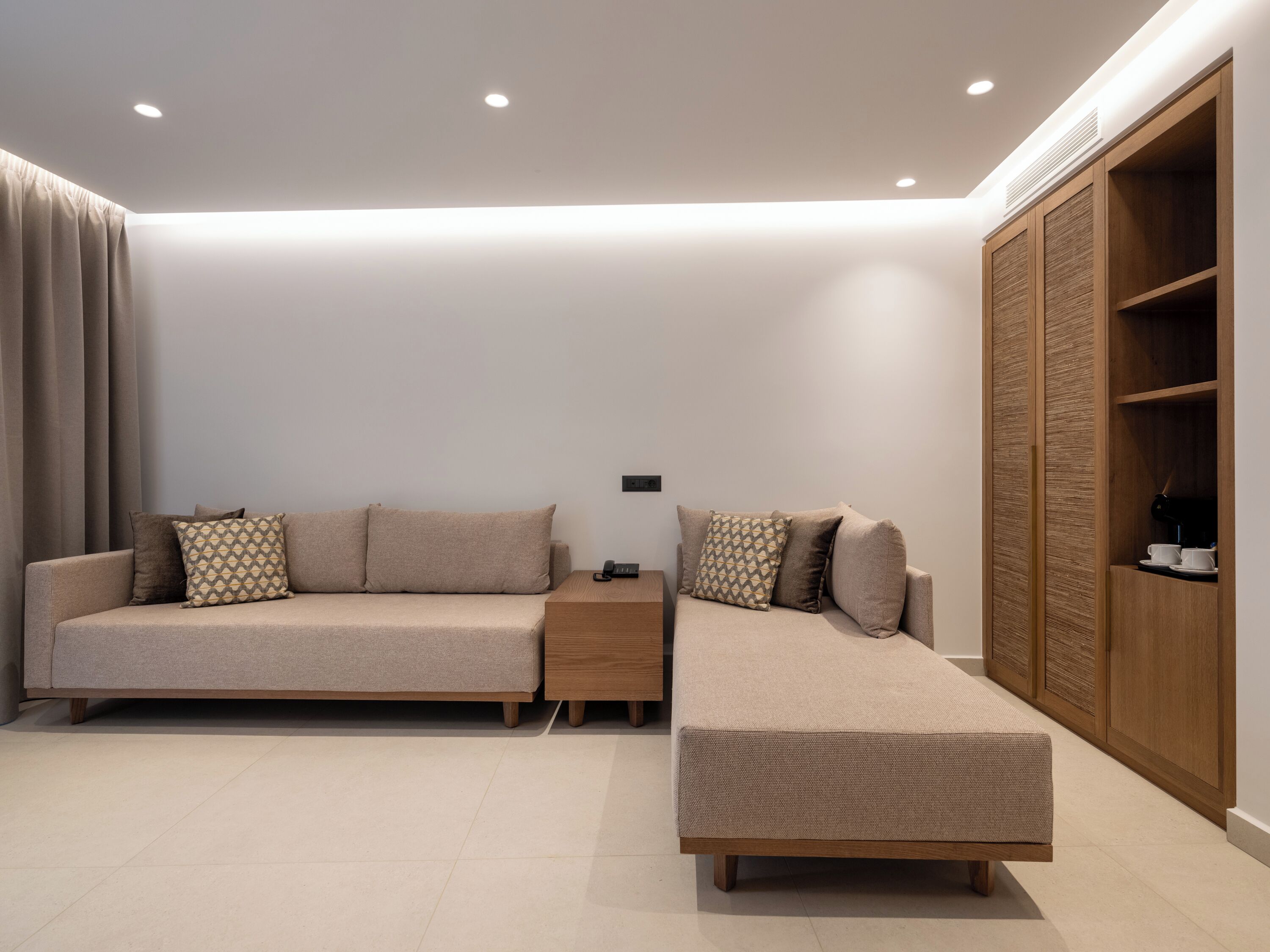 A modern living room with a sofa, ottoman, and wooden wardrobe.