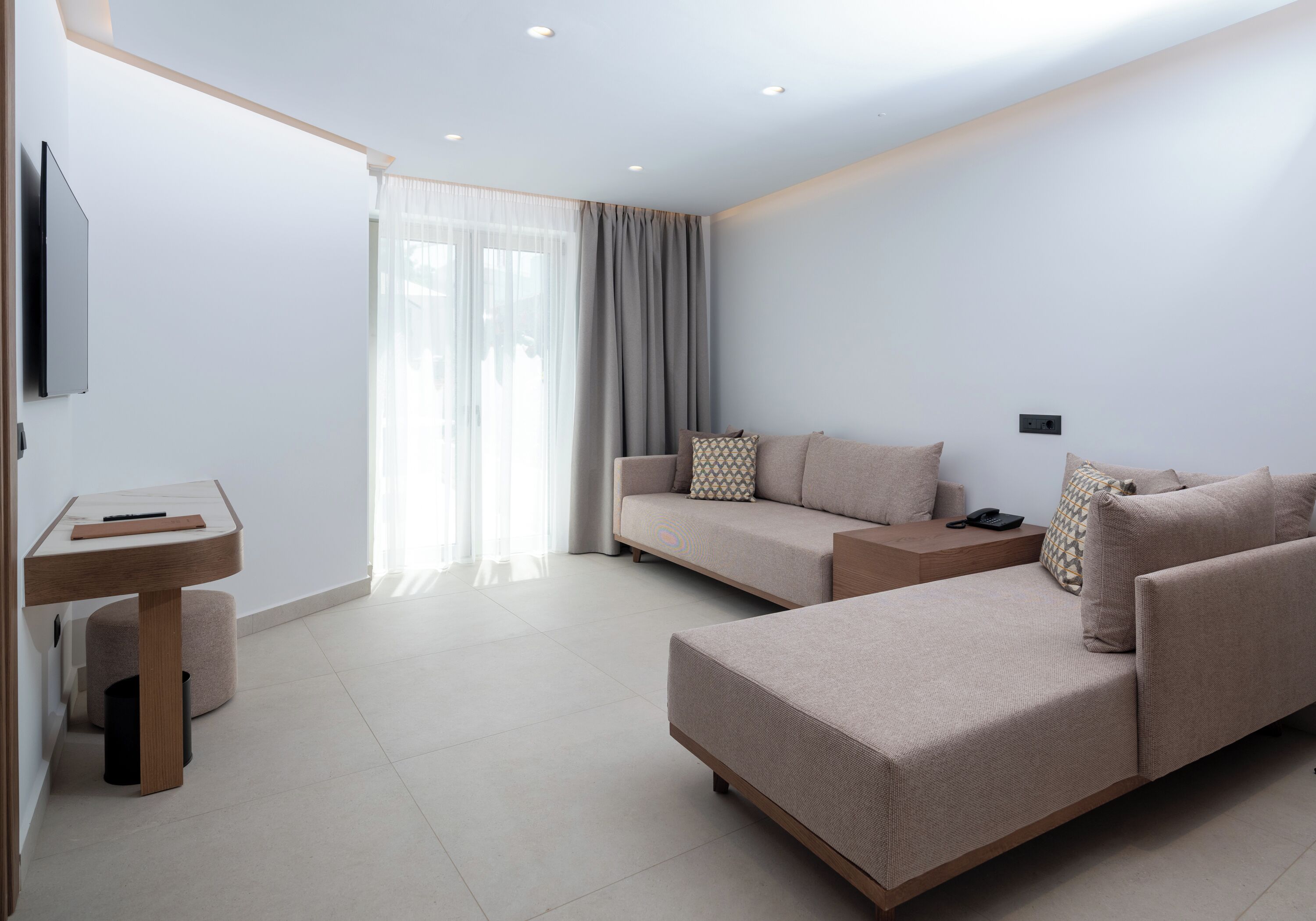 A modern living room with a sofa, ottoman, and a small table with a remote control.
