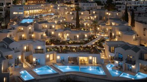 A modern hotel with multiple swimming pools, outdoor seating areas, and well-lit balconies. - Galaxy Suites Boutique Resort (Hersonissos)