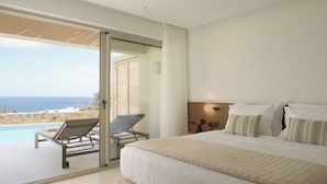 Un dormitorio con una cama grande, vistas al mar y un balcón con una silla.
