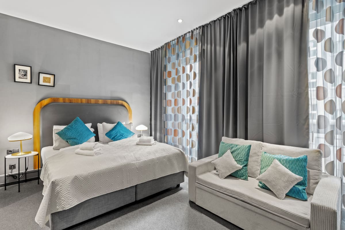 A modern hotel room with a large bed, a sofa, and a small table.