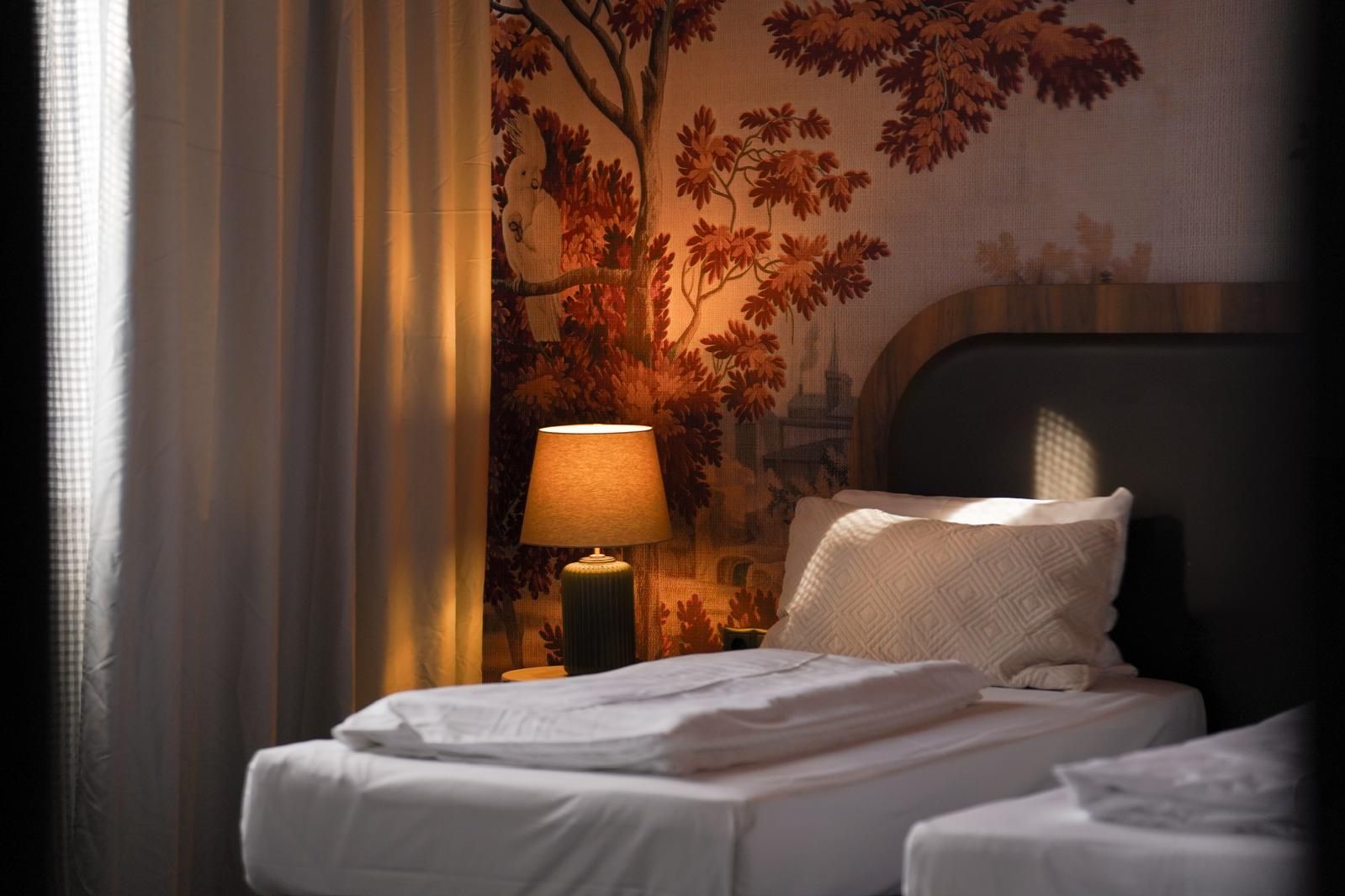 Una habitación de hotel con una cama, una lámpara y un mural en la pared.