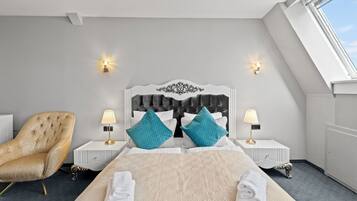 A modern hotel room with a large bed, two nightstands, a tufted armchair, and a skylight.