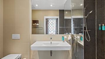 Une salle de bain moderne avec un lavabo blanc, des toilettes et un espace douche.