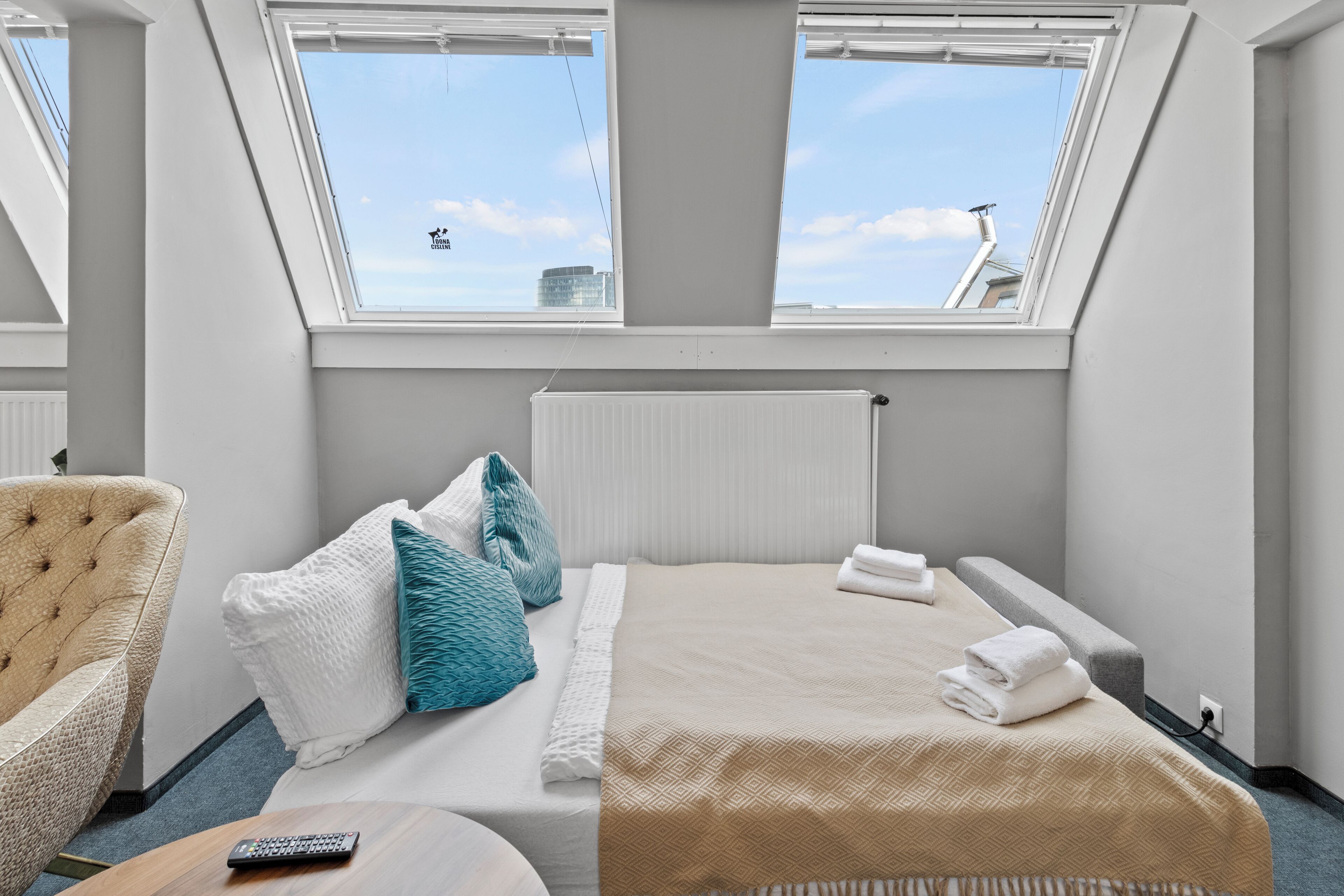 Una moderna camera d'albergo con un letto, una sedia, un tavolo e un lucernario.