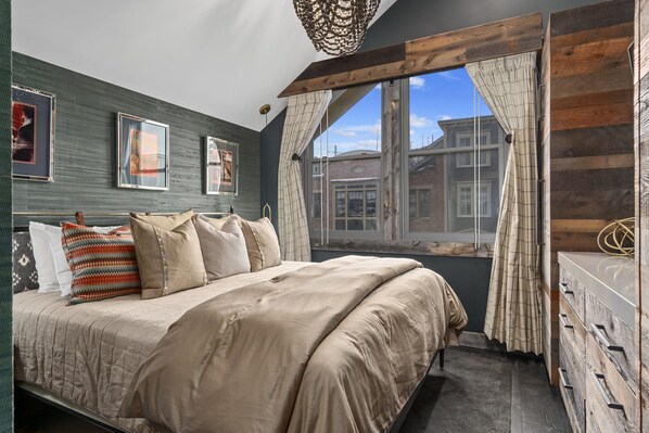 A bedroom with a large bed, a dresser, and a window with curtains.