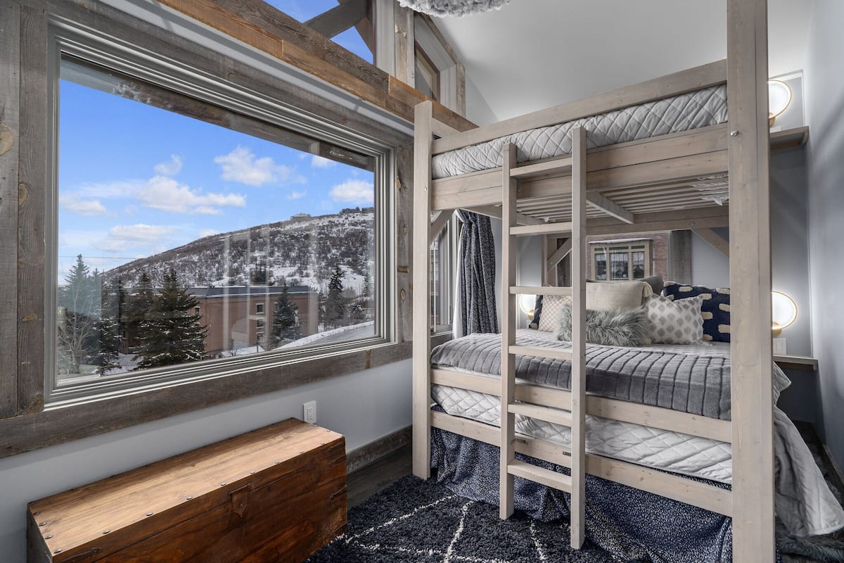 Habitación con literas y una ventana grande que da a un paisaje nevado.