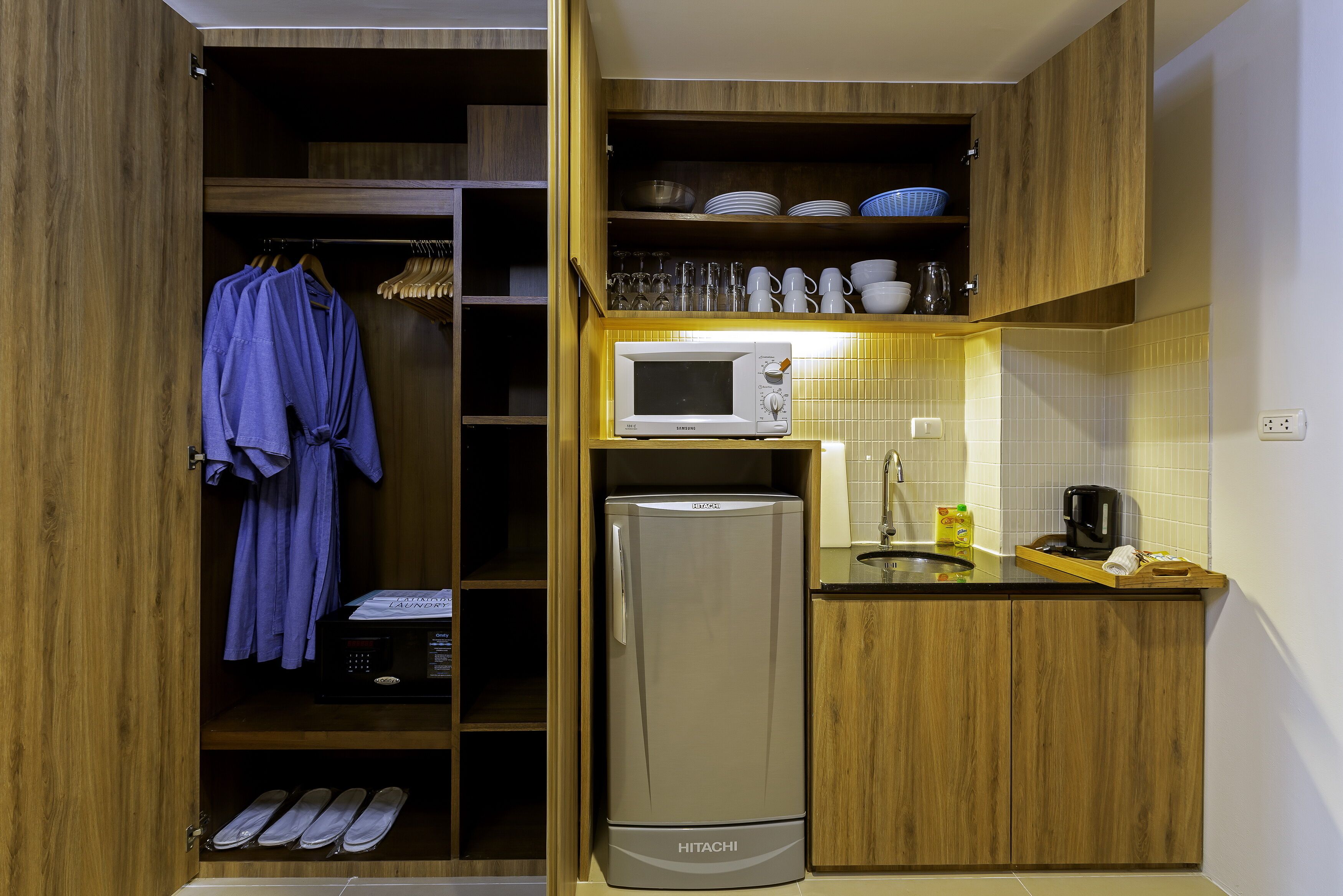 Una cocina compacta con microondas integrado, refrigerador y armarios de madera.