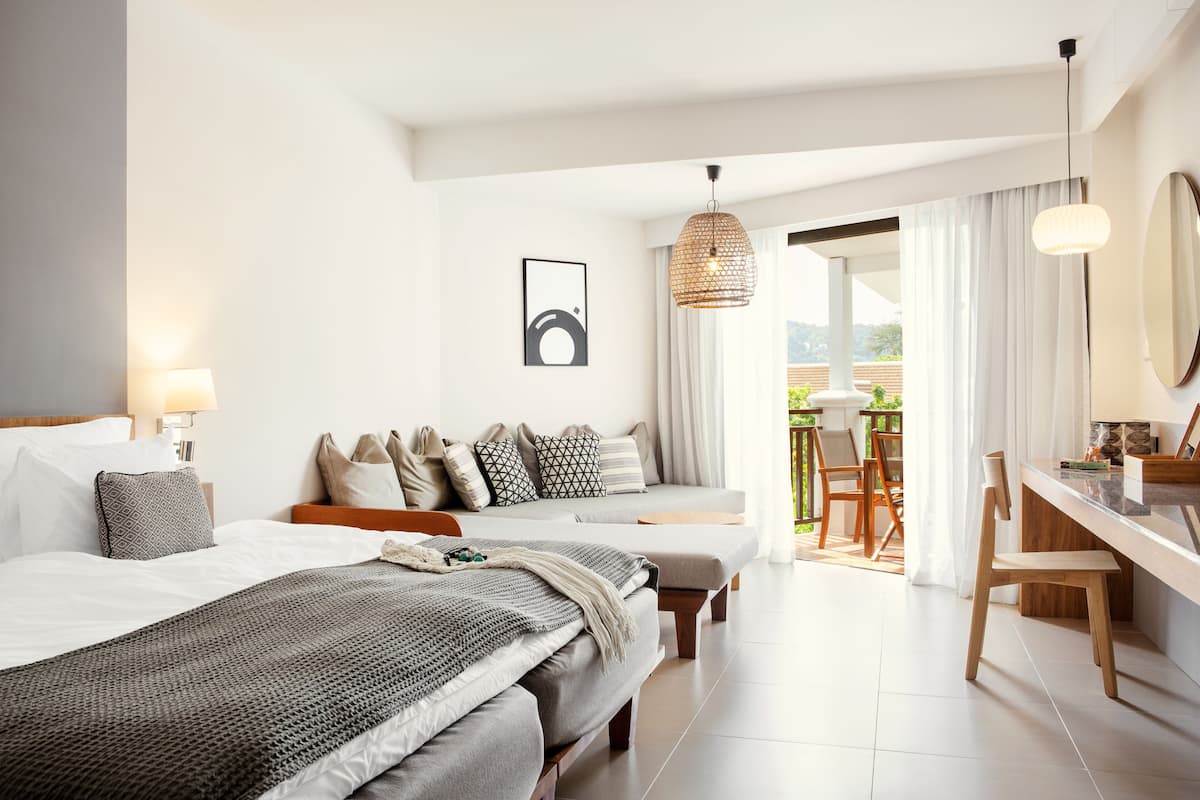 Habitación de hotel moderna con una cama grande, un escritorio y un balcón con vistas.
