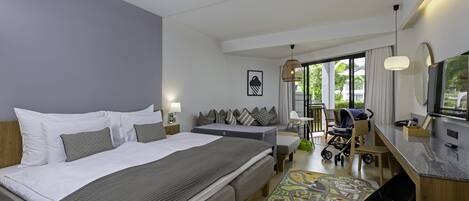 A modern hotel room with a large bed, a desk, a chair, a baby stroller, and a view of the outdoors.