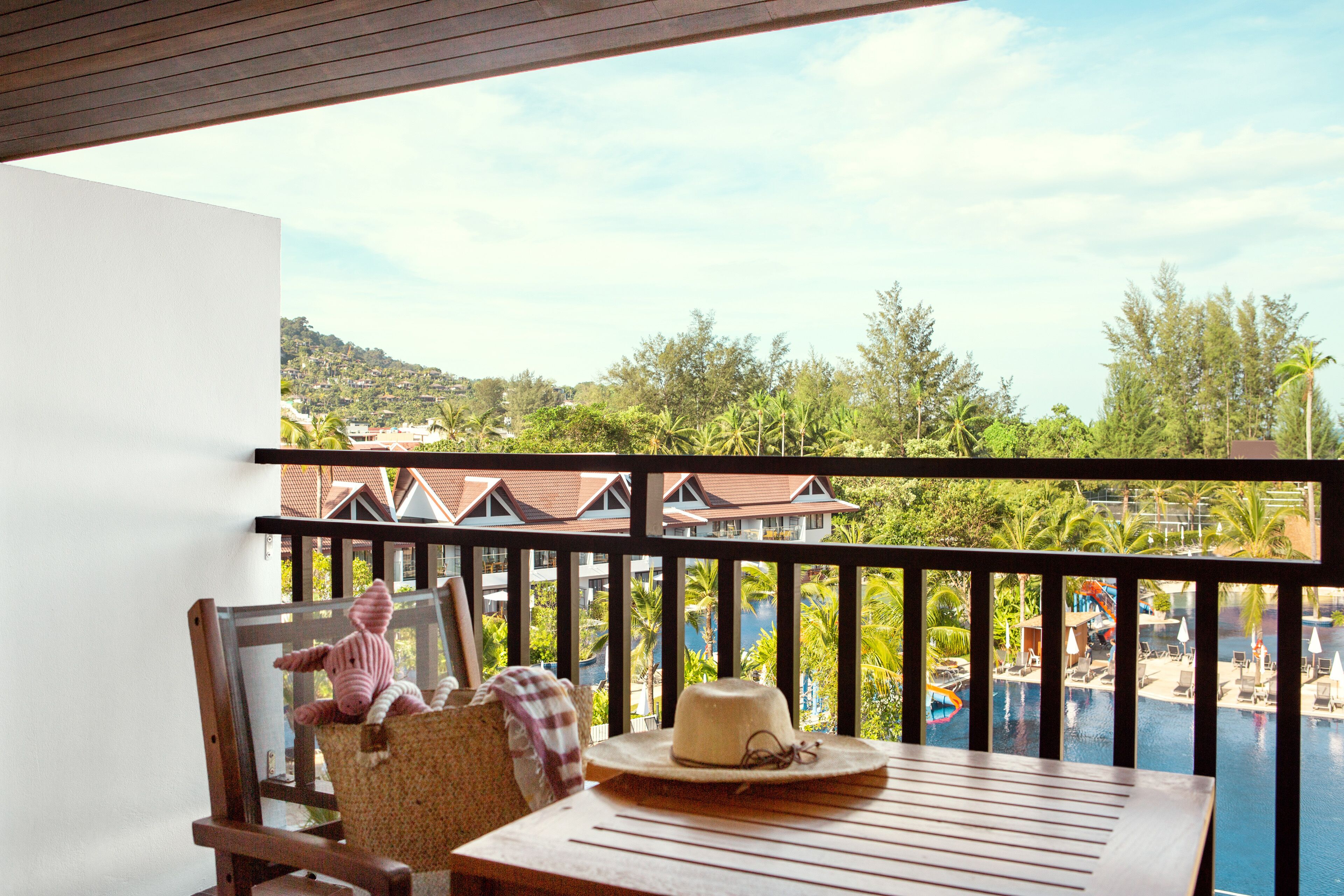 A balcony with a view of a resort area, including a pool and buildings.