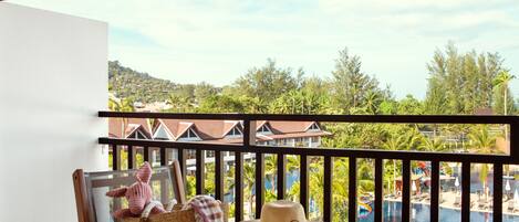 A balcony with a view of a resort area, including a pool and buildings.