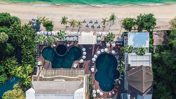 Eine Vogelperspektive eines Resorts mit mehreren Schwimmbecken, Zugang zum Strand und Palmen.