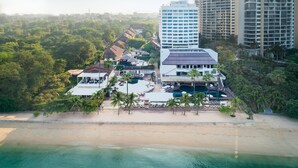 Vista aerea di un hotel sulla spiaggia con diversi edifici, una zona piscina e una spiaggia.