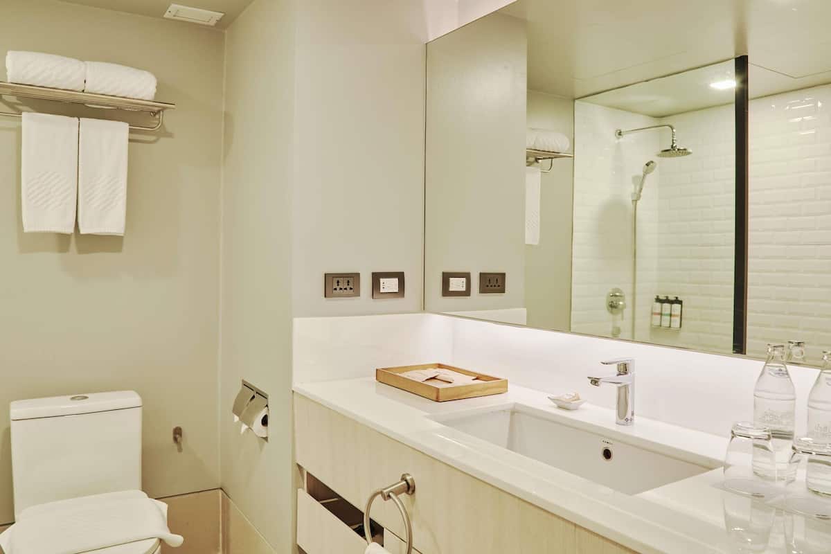 A modern bathroom with a large mirror, a bathtub, a toilet, and a sink.