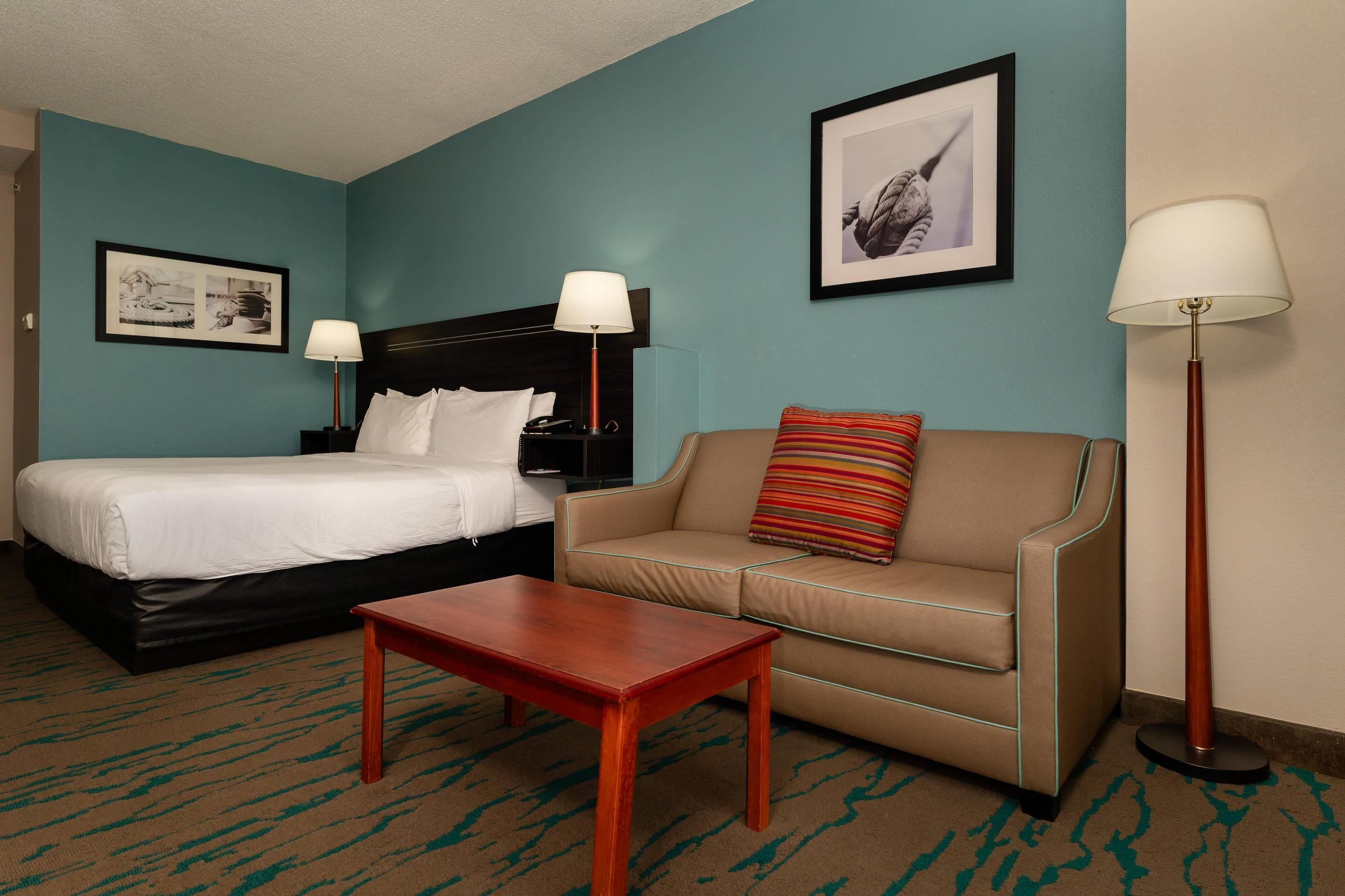 Ein Hotelzimmer mit Bett, Sofa, kleinem Tisch und zwei Lampen.